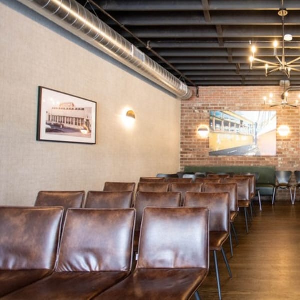 Rows of brown leather chairs in a modern event space with exposed brick and ductwork.