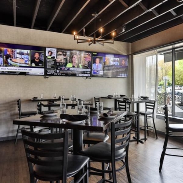 The Brookdale dining room with multiple TVs showing sports, set tables, and large windows.