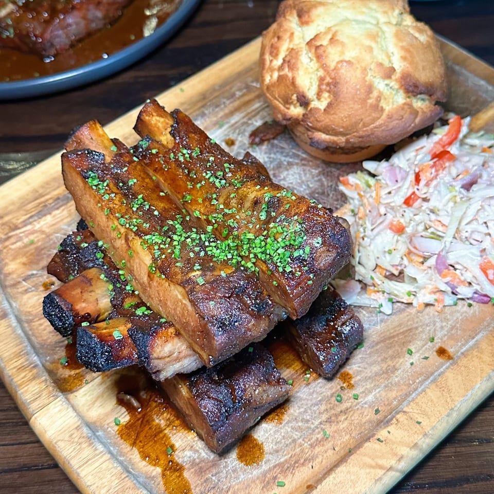 The Brookdale's BBQ ribs with coleslaw and a Yorkshire pudding on a wooden board.