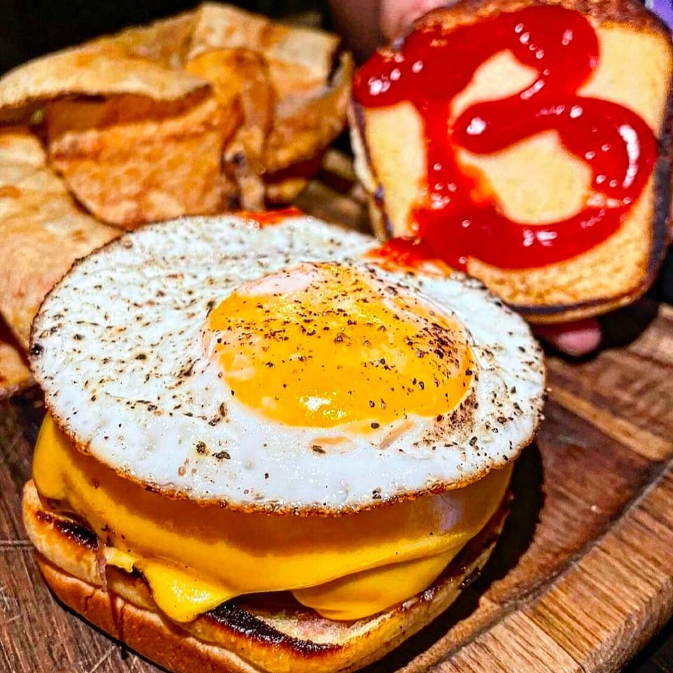 The Brookdale's burger with melted cheese and a fried egg, served with chips and ketchup.