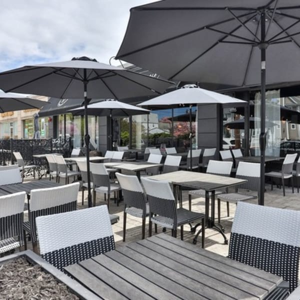 The Brookdale's outdoor patio with numerous tables, chairs, and large black umbrellas under a bright sky.