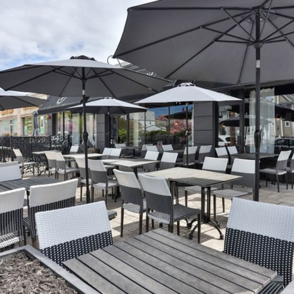 The Brookdale's outdoor patio with numerous tables, chairs, and large black umbrellas under a bright sky.