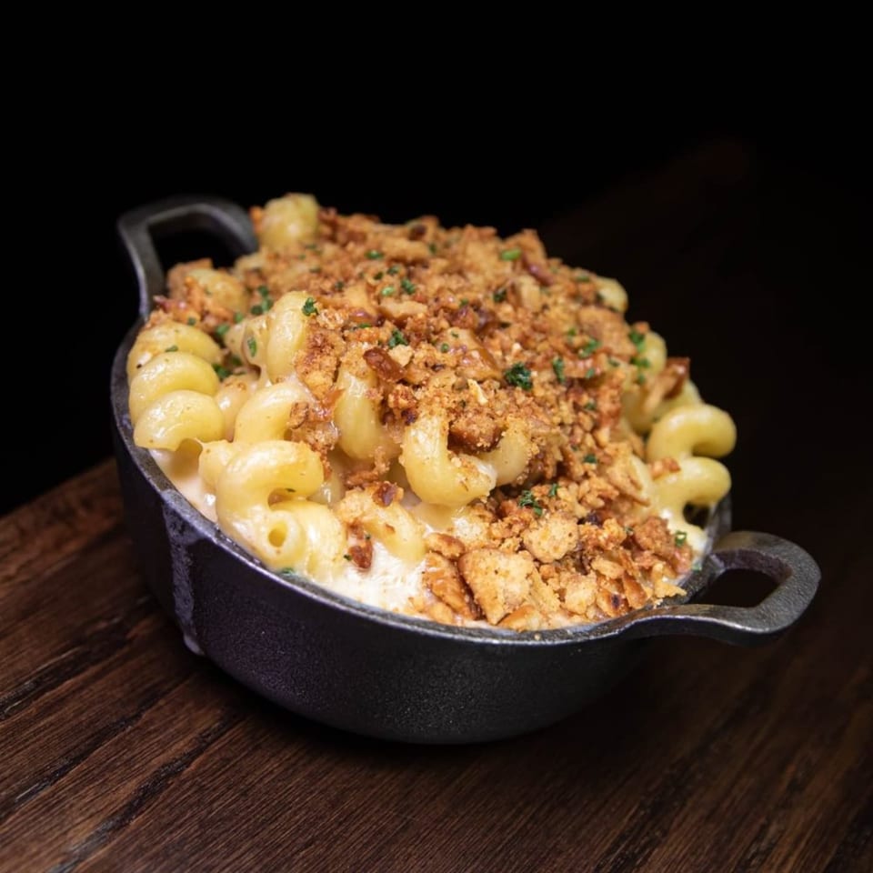 Creamy mac and cheese with a crispy breadcrumb topping in a black cast iron dish.
