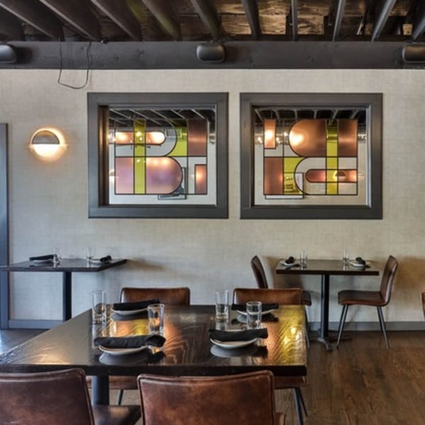 The Brookdale's dining room with dark wooden tables, brown leather chairs, and stained-glass windows.